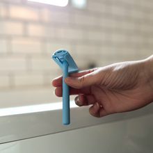 Load image into Gallery viewer, Woman holding a pale blue safety razor with matching coloured head protector - Shoreline Shaving