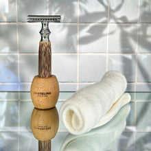 Load image into Gallery viewer, Soft white bamboo shaving cloth rolled up next to a bamboo safety razor in a stand - Shoreline Shaving