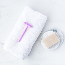 Load image into Gallery viewer, Sustainable light purple safety razor lay on a white towel with a shaving soap beside it - Shoreline Shaving