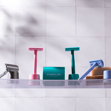 Load image into Gallery viewer, A pale blue safety razor travel set on a clear bathroom shelf, along with various other colours of razors - Shoreline Shaving
