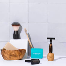 Load image into Gallery viewer, Storm grey bamboo safety razor in matching bamboo stand, surrounded by bathroom accessories including shaving soap, toothbrush and blade tin - Shoreline Shaving

