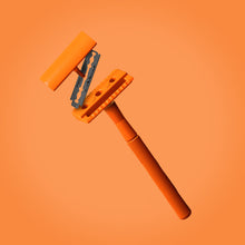 Load image into Gallery viewer, A three piece orange safety razor with blade floating on an orange background - Shoreline Shaving
