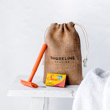 Load image into Gallery viewer, Orange Reusable Safety Razor leaning on a hessian bag with a white towel in the foreground - Shoreline Shaving
