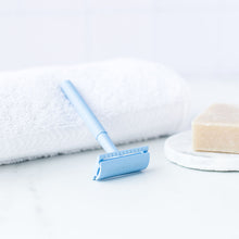 Load image into Gallery viewer, Pale Blue safety razor resting on a white towel next to shaving soap - Shoreline Shaving
