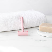 Load image into Gallery viewer, Sustainable pastel pink safety razor lay on a white towel with a shaving soap beside it - Shoreline Shaving
