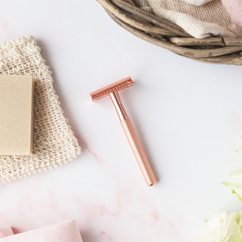 Rose gold safety razor lay a marbled surface with a natural shaving soap beside it - Shoreline Shaving
