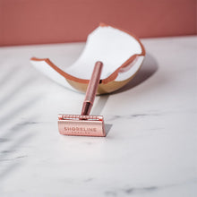 Load image into Gallery viewer, Rose gold safety razor resting on pieces of a shaving bowl - Shoreline Shaving

