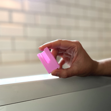 Load image into Gallery viewer, Woman holding a light purple safety razor head protector between her fingers - Shoreline Shaving
