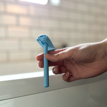 Load image into Gallery viewer, Woman holding a pale blue safety razor with matching coloured head protector - Shoreline Shaving
