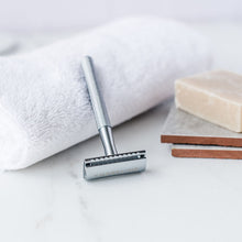 Load image into Gallery viewer, Reusable silver metal safety razor leaning on a white towel with shaving soap - Shoreline Shaving
