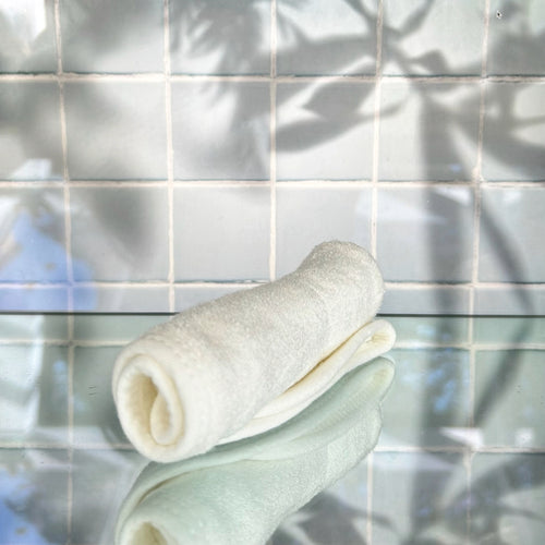 Soft white bamboo shaving cloth rolled up on a reflective surface - Shoreline Shaving