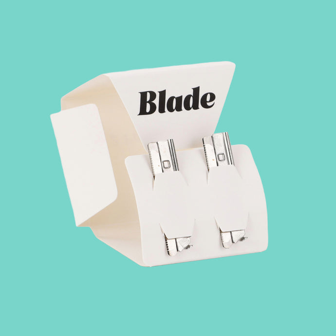 Dermaplaner refill blades in a pack of two, standing, on a teal background - Shoreline Shaving
