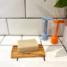 Load image into Gallery viewer, Grooved olive wood soap dish with natural shaving bar on top, beside two Shoreline Shaving safety razors in stands
