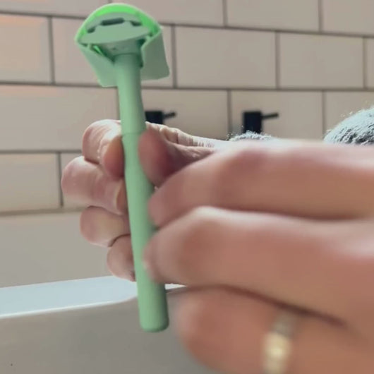 Video of a woman applying a green razor head protector to the matching safety razor - Shoreline Shaving