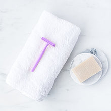 Load image into Gallery viewer, Sustainable light purple safety razor lay on a white towel with a shaving soap beside it - Shoreline Shaving
