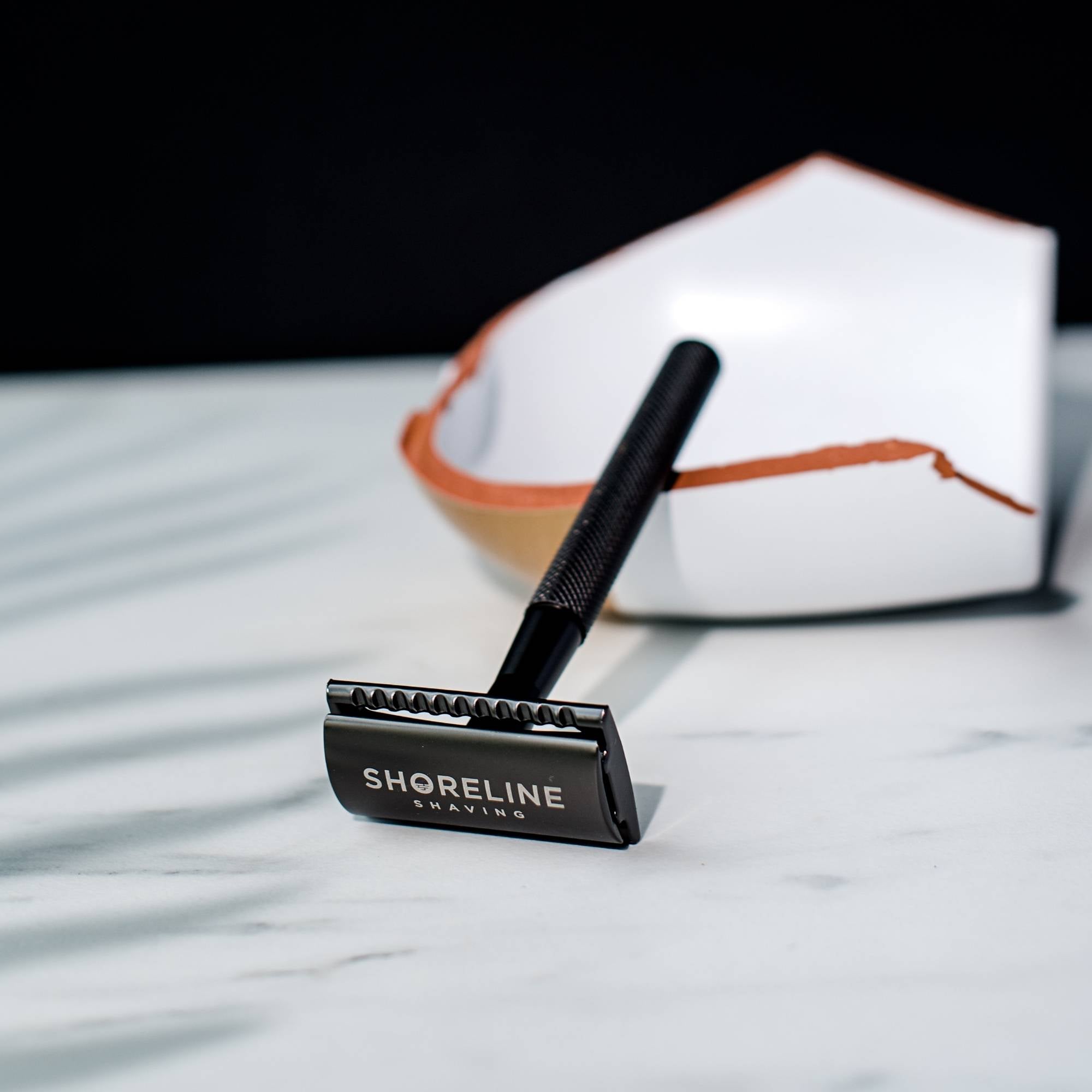 Closeup of matte black safety razor with the Shoreline Shaving logo in view