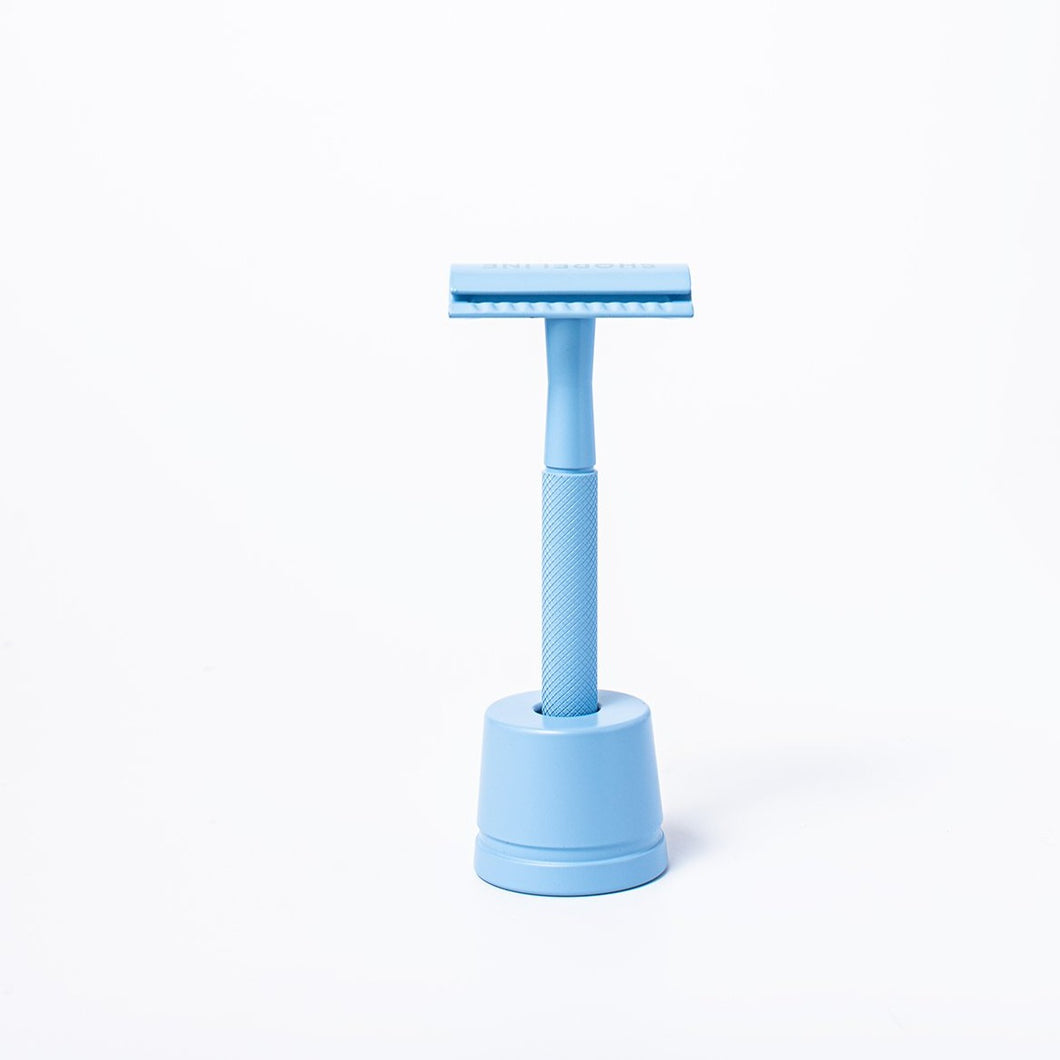 Pale blue reusable metal safety razor inside a blue razor stand - Shoreline Shaving