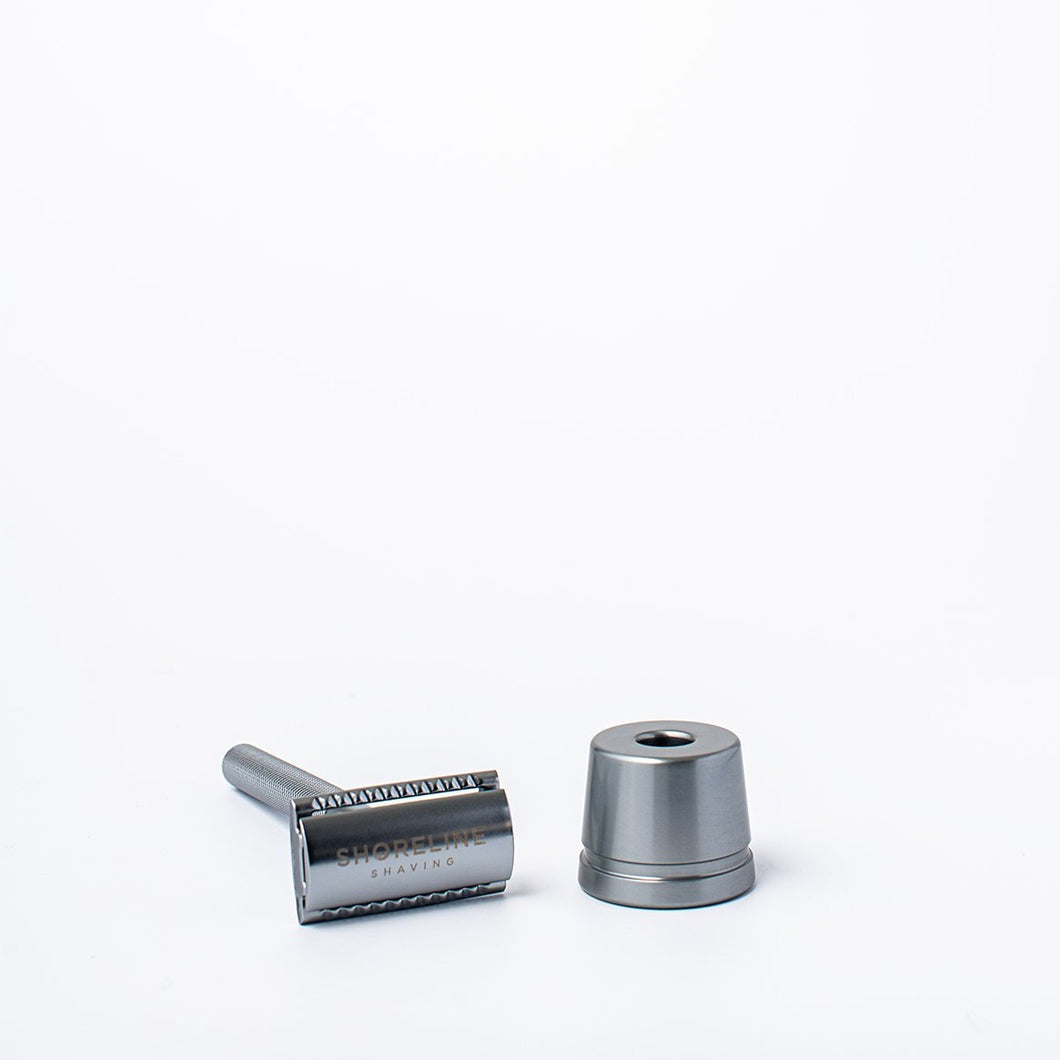 Silver metal reusable safety razor next to a silver razor stand - Shoreline Shaving