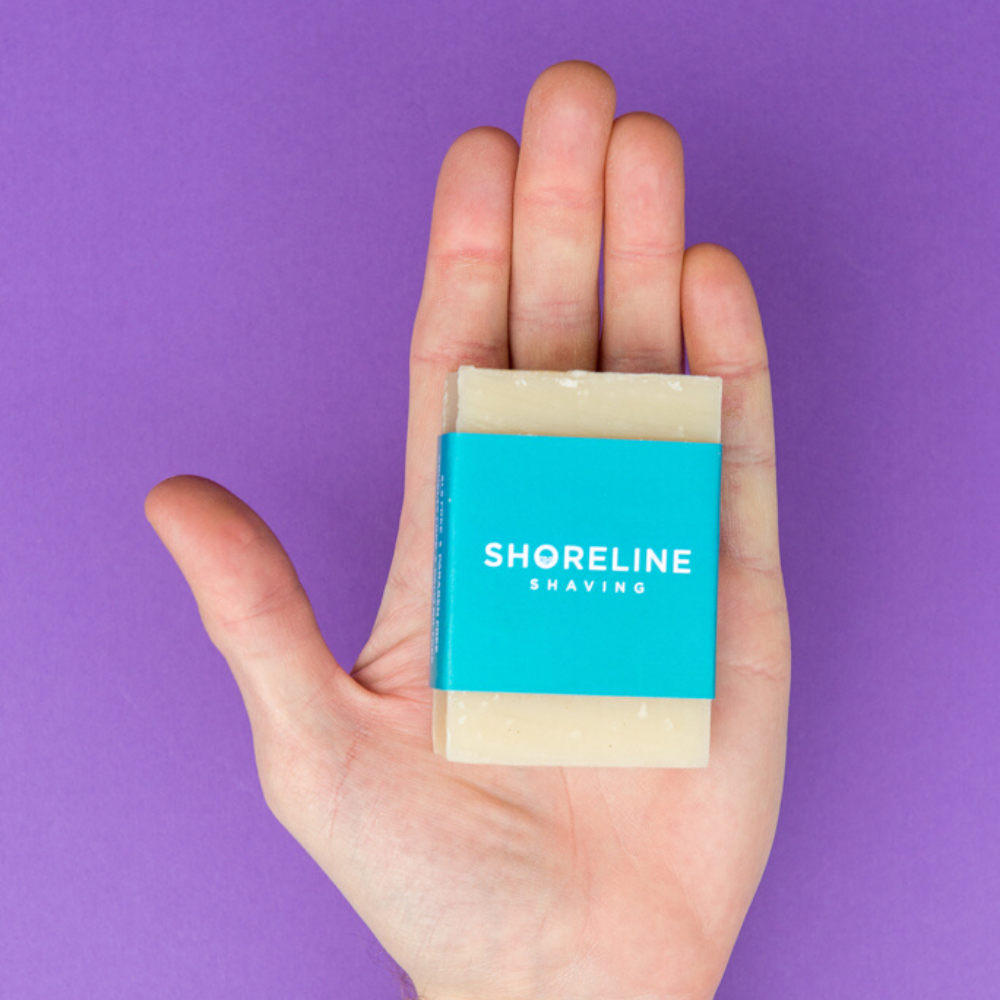 Natural shaving soap in a hand with a purple background - Shoreline Shaving