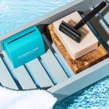 Load image into Gallery viewer, Matte black safety razor on top of natural shaving soap bar in a soap rest, next to a teal blade tin - Shoreline Shaving
